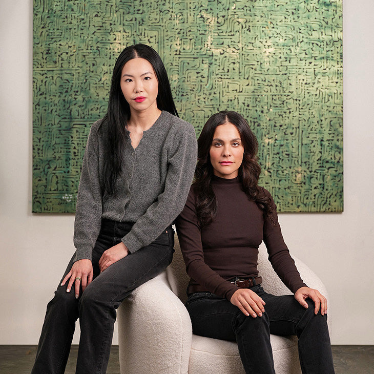 Founders sitting on a white stool in front of a green abstract painting.