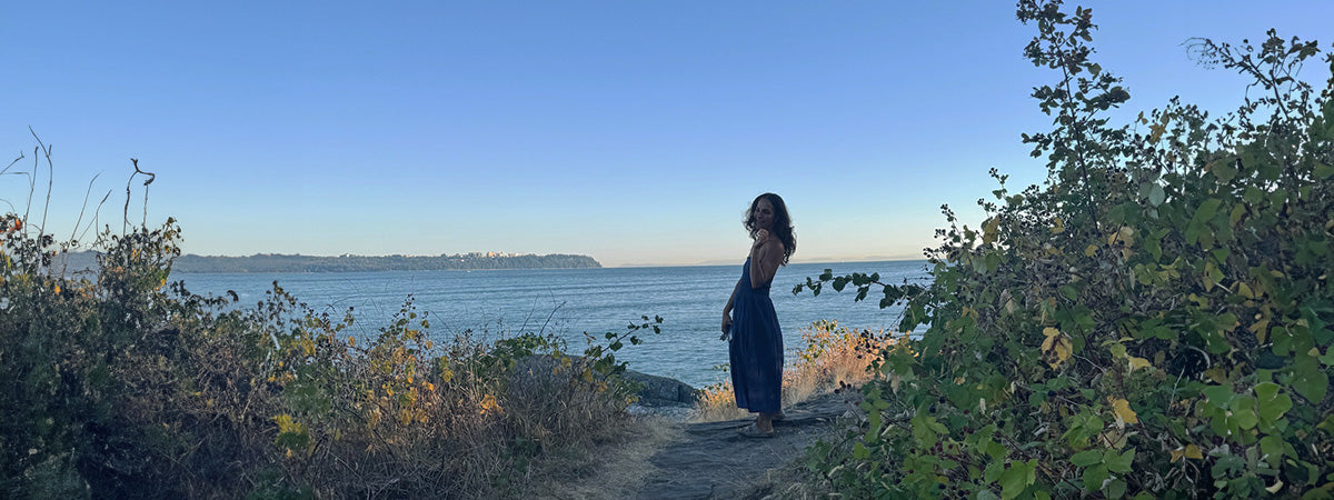 Person standing by a body of water with a clear blue sky