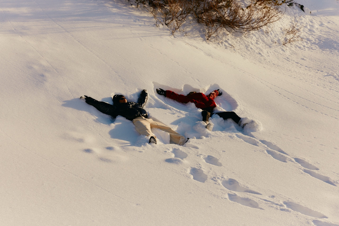 Two people making snow angels - complimentary holiday shipping until December 18