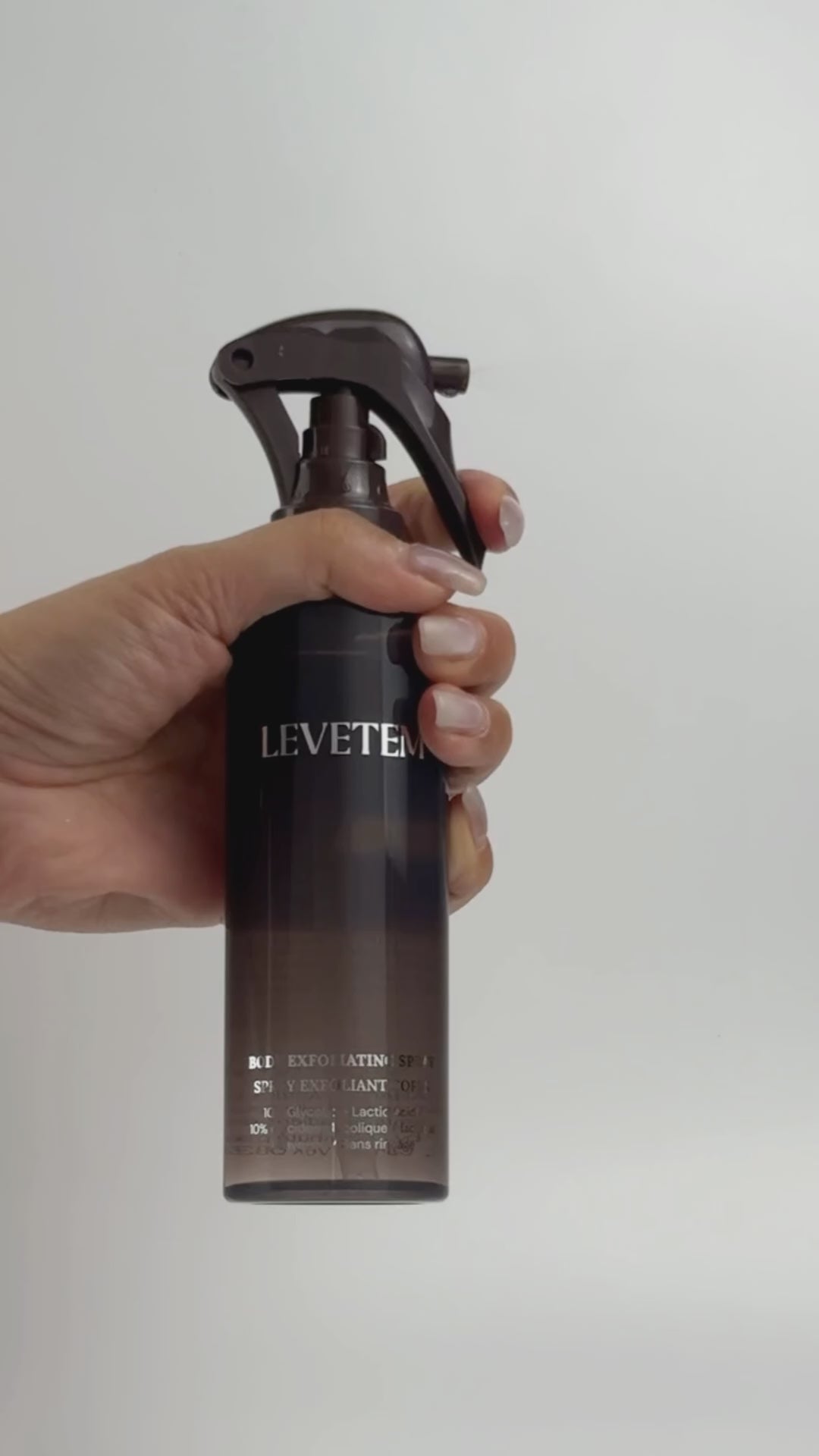 Spraying Levetem Body Exfoliating Spray against a neutral background